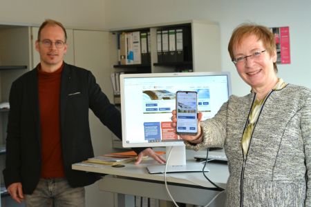 Zu sehen sind Amtsleitung Petra Bolte und Mitarbeiter Guido Kemmer mit Handy und Computer, auf denen das Chancenportal gezeigt wird